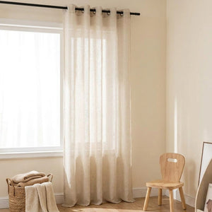 Voilage tulle beige dans une chambre d'enfant douce avec petite chaise en bois