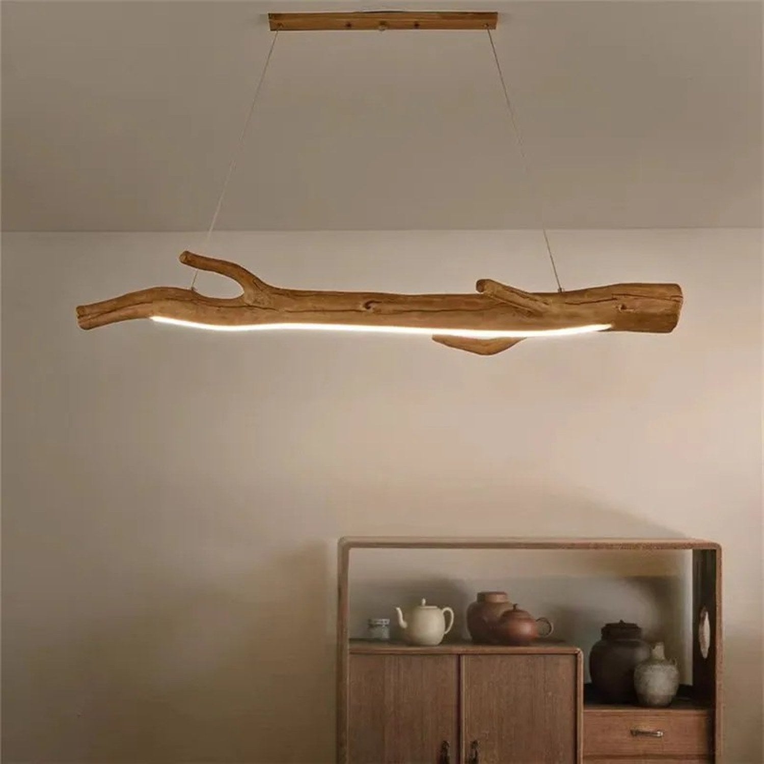 Lustre suspendu en résine forme branche allumé au dessus d'un meuble bas en bois