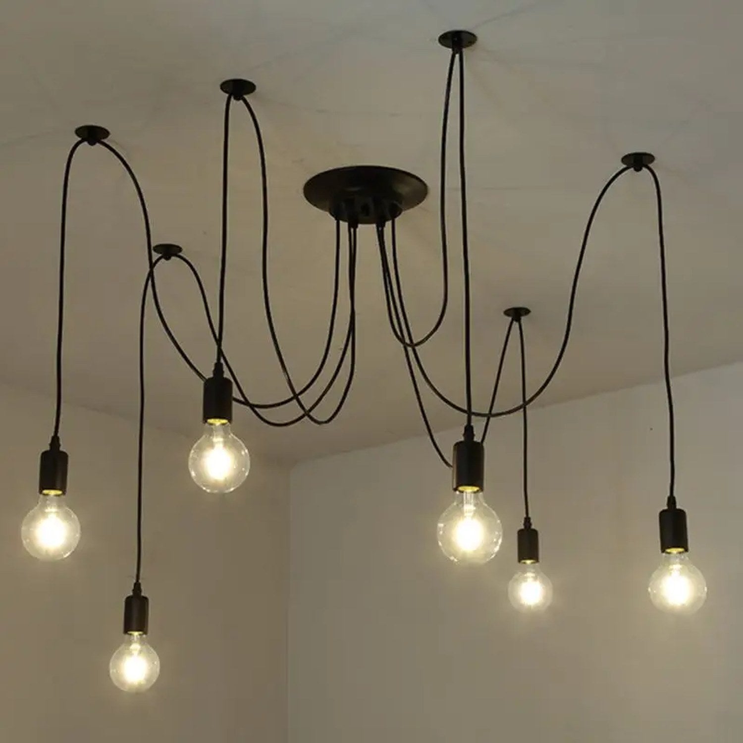 Lustre araignée noir installé au plafond avec ses ampoules à filament allumées
