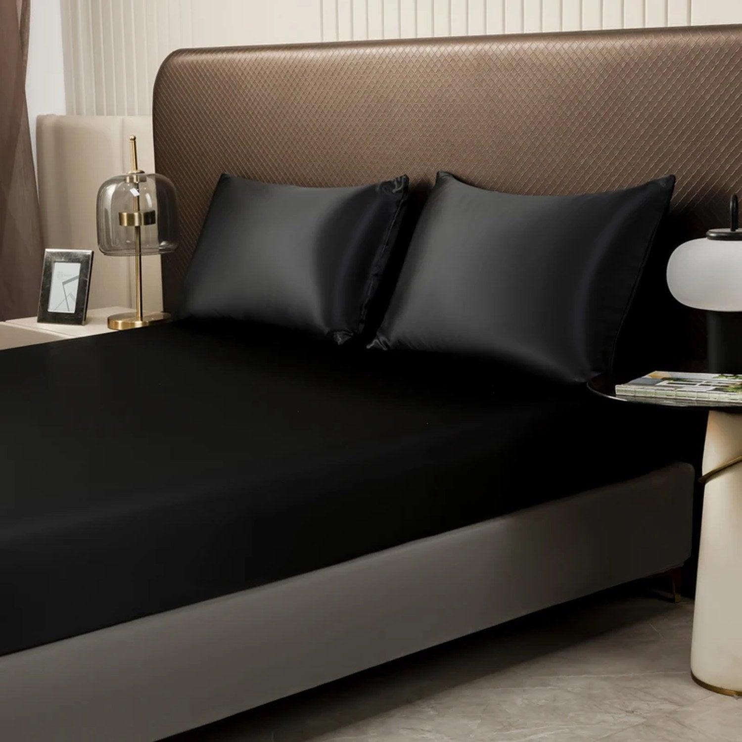 Vue rapprochée du drap housse satin noir avec taies d'oreiller sur un lit