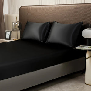 Vue rapprochée du drap housse satin noir avec taies d'oreiller sur un lit