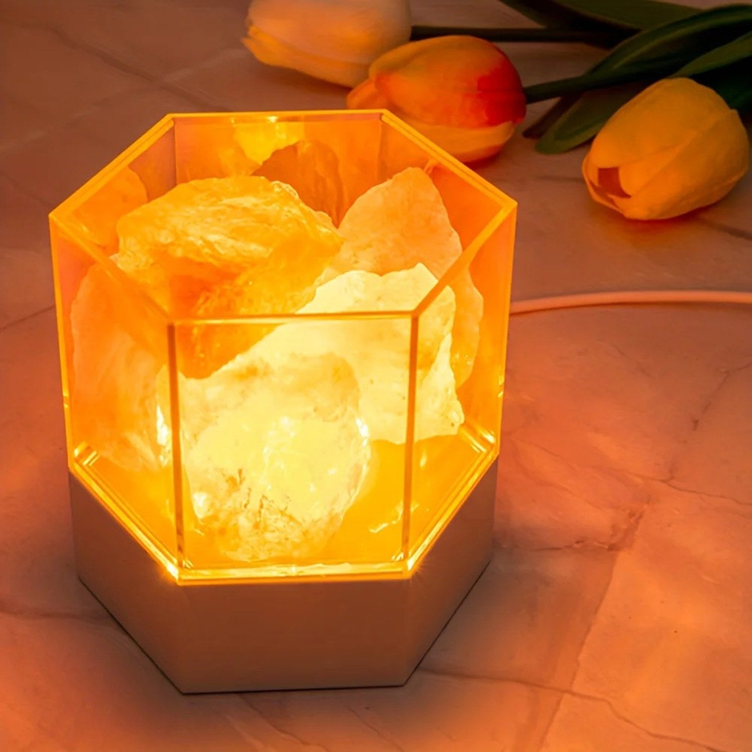 Lampe de sel hexagonale allumée sur une table avec des tulipes
