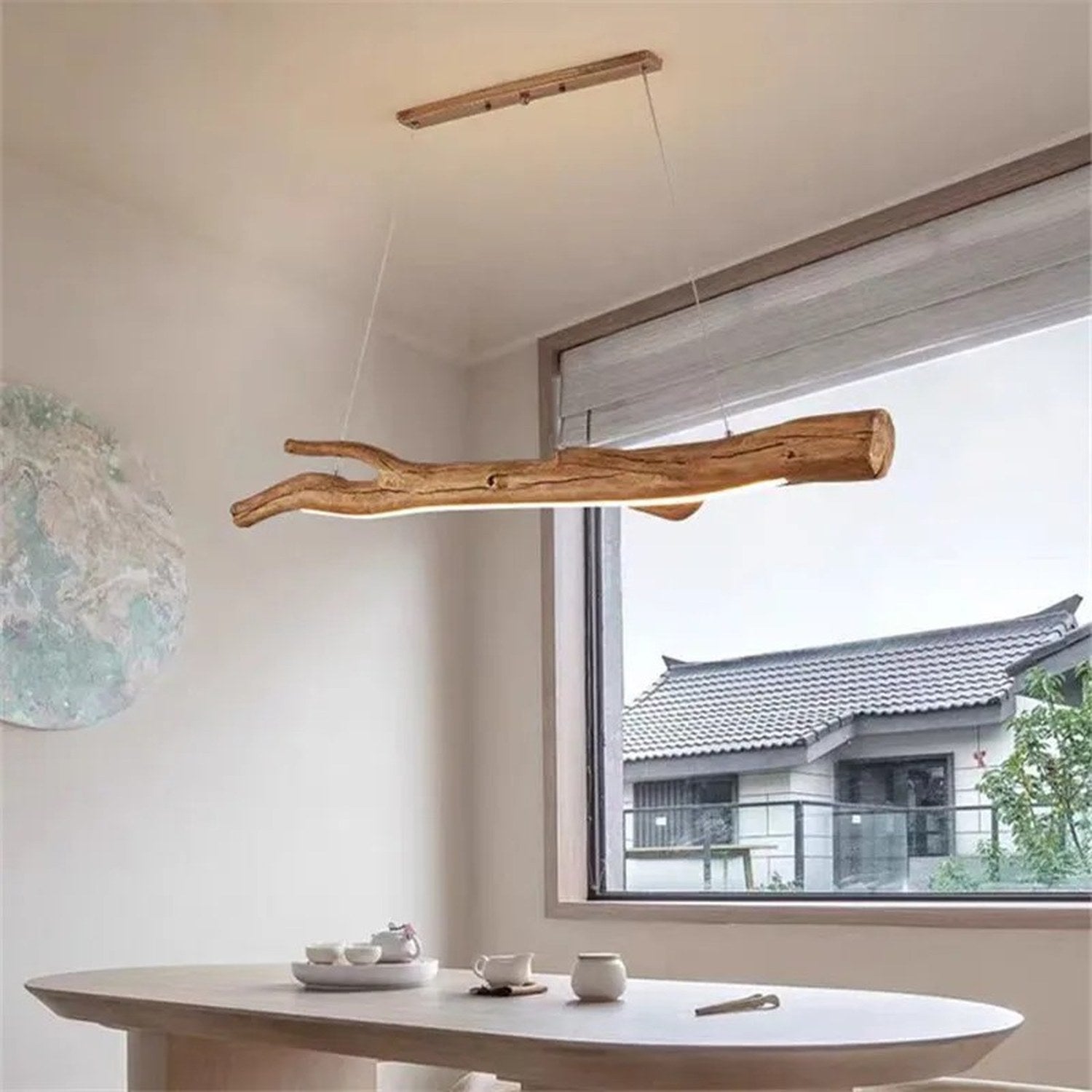 Lustre suspendu en résine forme branche près d'une fenêtre avec vue sur toiture