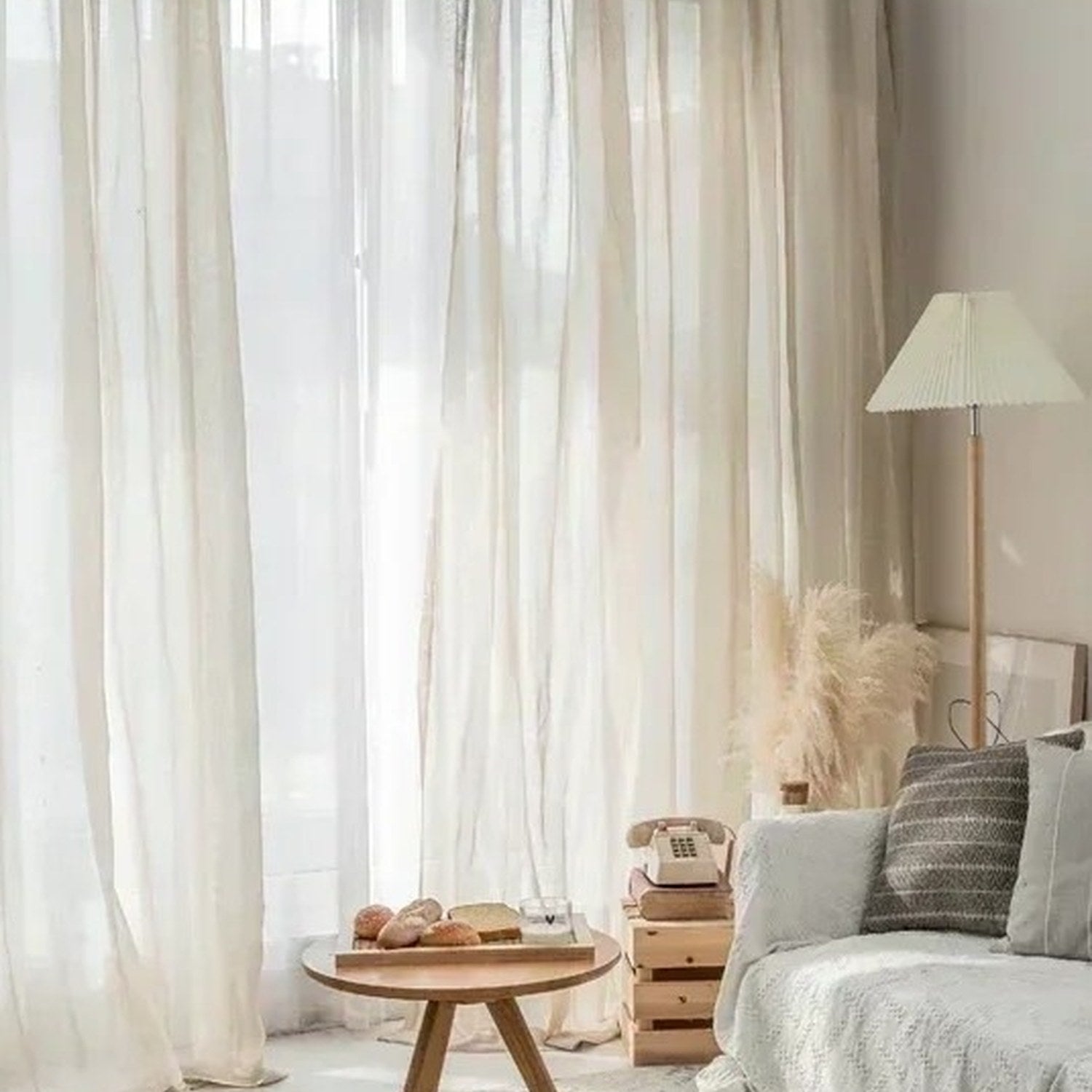 Voilage tulle beige dans un salon lumineux avec lampadaire et table basse en bois