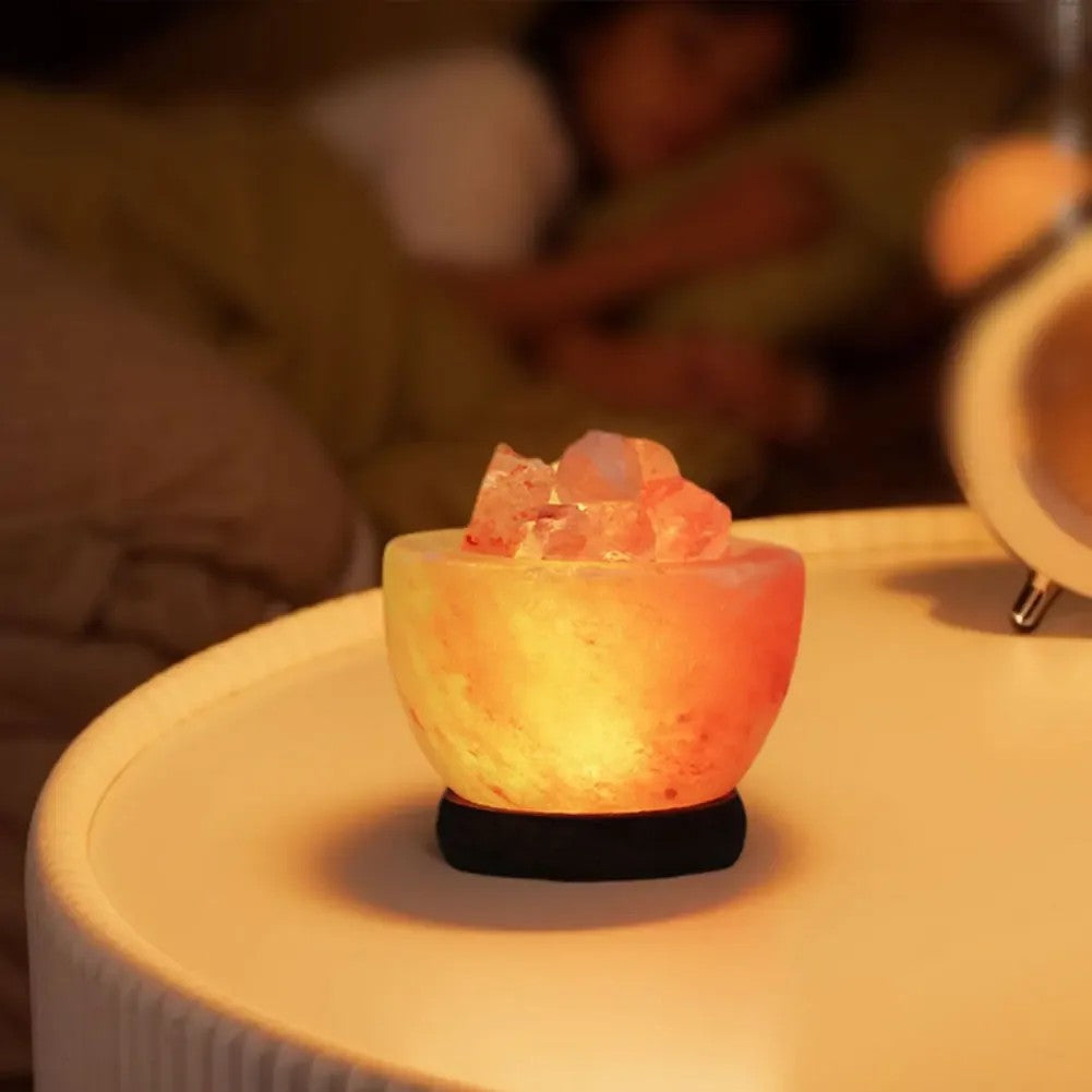 Lampe de sel de l'Himalaya allumée sur une table de chevet dans une chambre tamisée