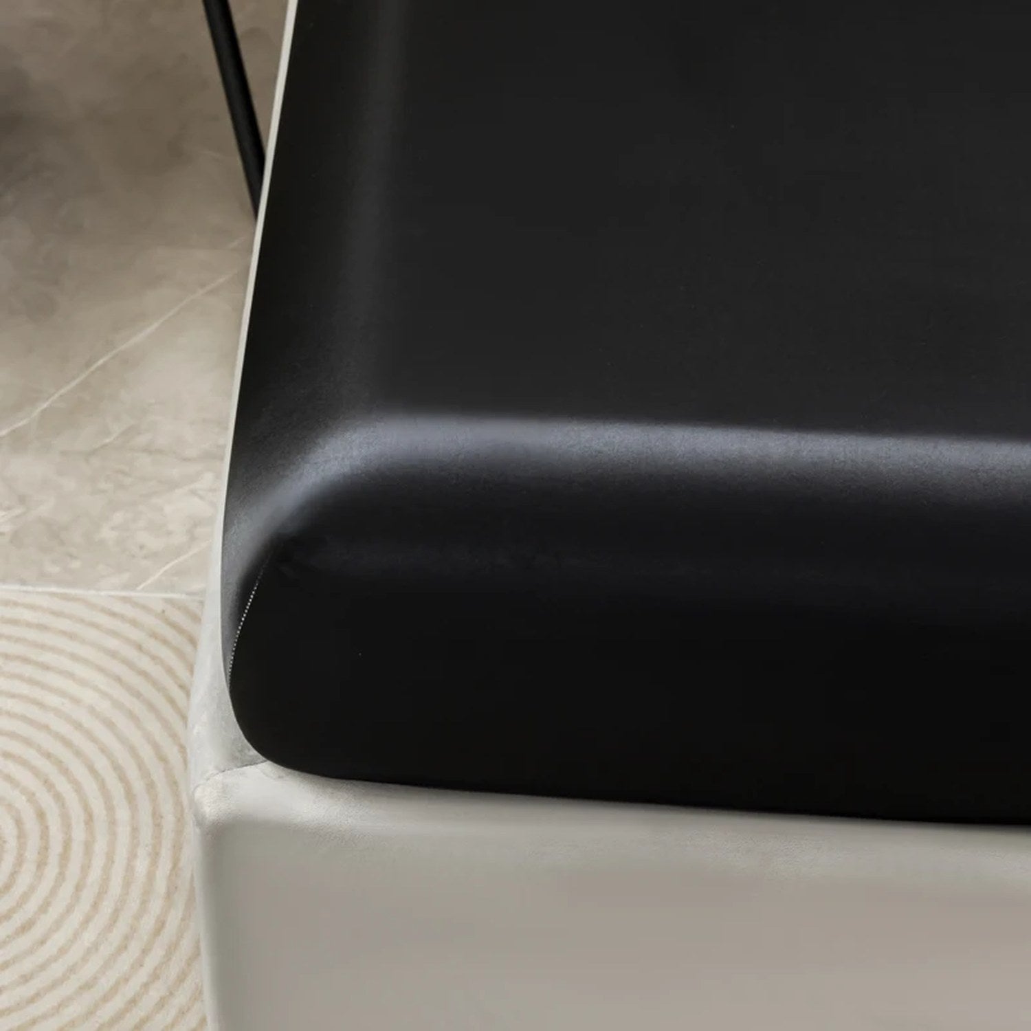 Coin du drap housse satin noir avec bande élastique ajustée au matelas