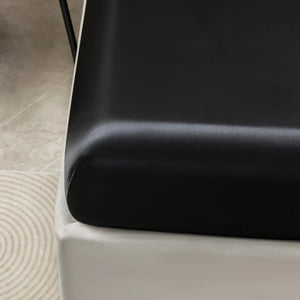 Coin du drap housse satin noir avec bande élastique ajustée au matelas