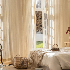 Rideau en gaze beige suspendu près d'un lit dans une chambre cocooning