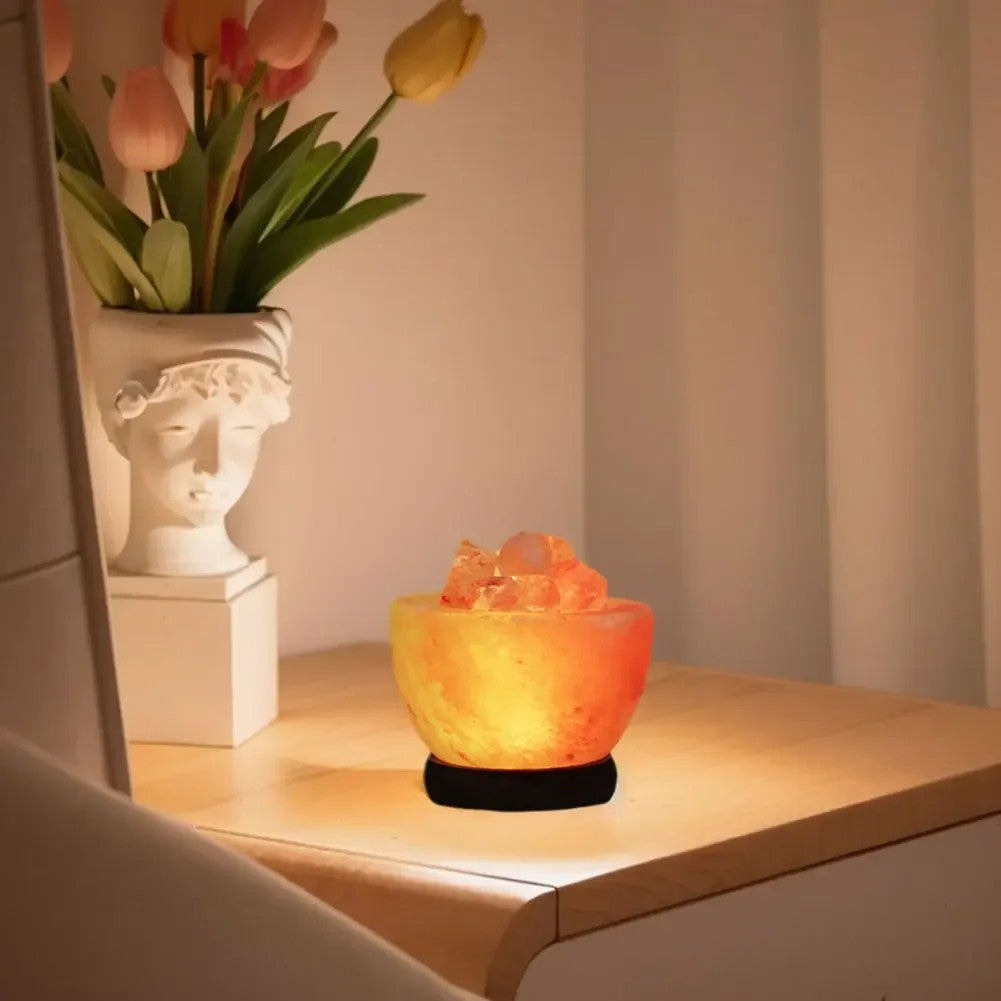 Lampe de sel de l'Himalaya allumée sur une étagère en bois avec un vase de tulipes