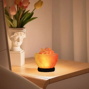 Lampe de sel de l'Himalaya allumée sur une étagère en bois avec un vase de tulipes