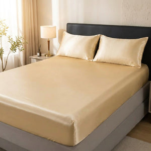 Drap housse en satin doré champagne sur un lit dans une chambre lumineuse