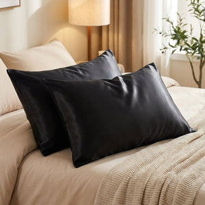Deux taies d'oreiller en satin noir sur un lit