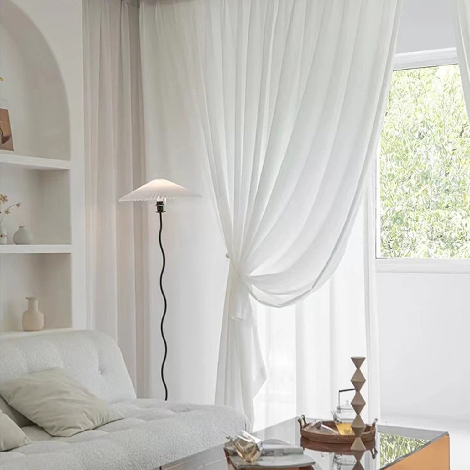 Voilage blanc dans un salon cosy avec lampadaire abat-jour plissé et vase sur étagère
