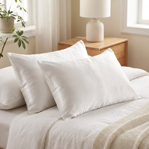 Deux taies d'oreiller en satin blanc sur un lit
