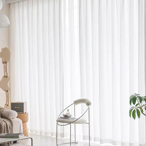 Voilage blanc dans un salon épuré avec chaise ronde en métal et plante verte