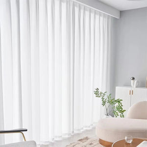Voilage blanc du sol au plafond dans une chambre grise avec meuble d'appoint et plante verte