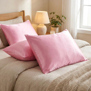 Deux taies d'oreiller en satin rose sur un lit