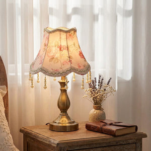 Abat-jour rose franges dans une chambre romantique sur table de nuit