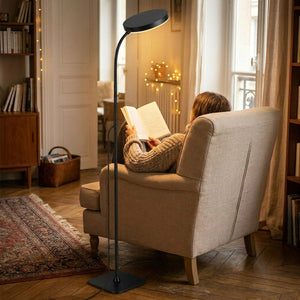 Personne lisant dans un fauteuil éclairée par un lampadaire liseuse LED col de cygne noir