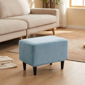 Housse de repose-pieds en velours bleu posée sur un pouf dans un salon cosy