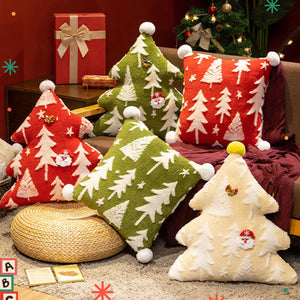 Coussins de Noël brodés avec motif sapin en relief, disposés sur un canapé et un tapis, créant une ambiance chaleureuse et festive dans un salon.