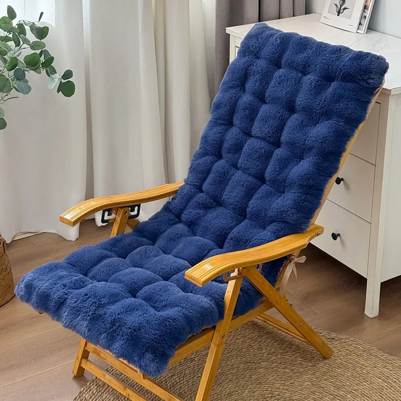 Un coussin de chaise longue moelleux en peluche avec capitonnage épais installé sur une chaise longue inclinable en bois, créant un espace de détente confortable dans un intérieur chaleureux.
