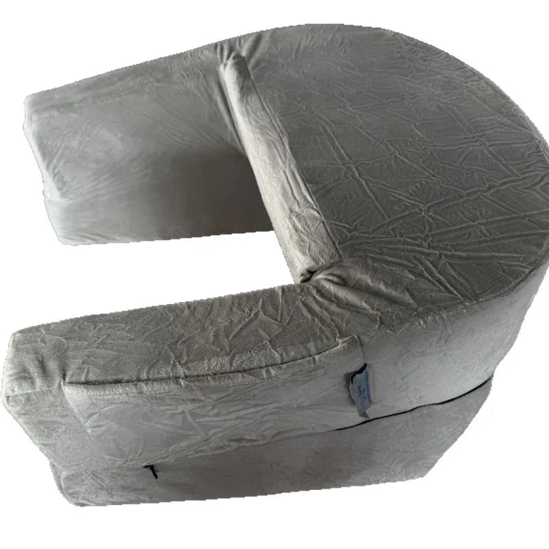 Coussin de lecture pratique avec accoudoirs posé sur les jambes d’une personne assise sur un canapé, offrant une surface stable pour lire un livre.