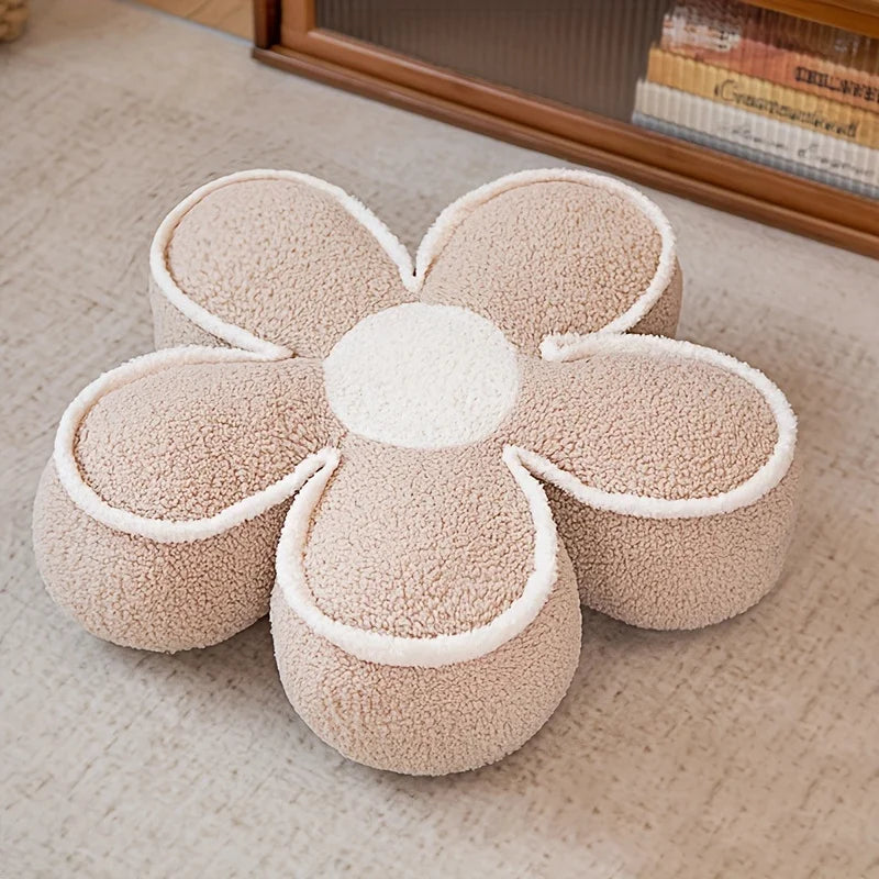 Coussin de sol doux en forme de fleur beige, composé de cinq pétales épais et d’un centre rond, posé sur un sol clair dans un intérieur chaleureux.
