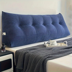Coussin lit capitonné avec fermeture éclair installé contre une tête de lit, au capitonnage structuré, posé sur un lit avec plaid texturé et plateau petit déjeuner.
