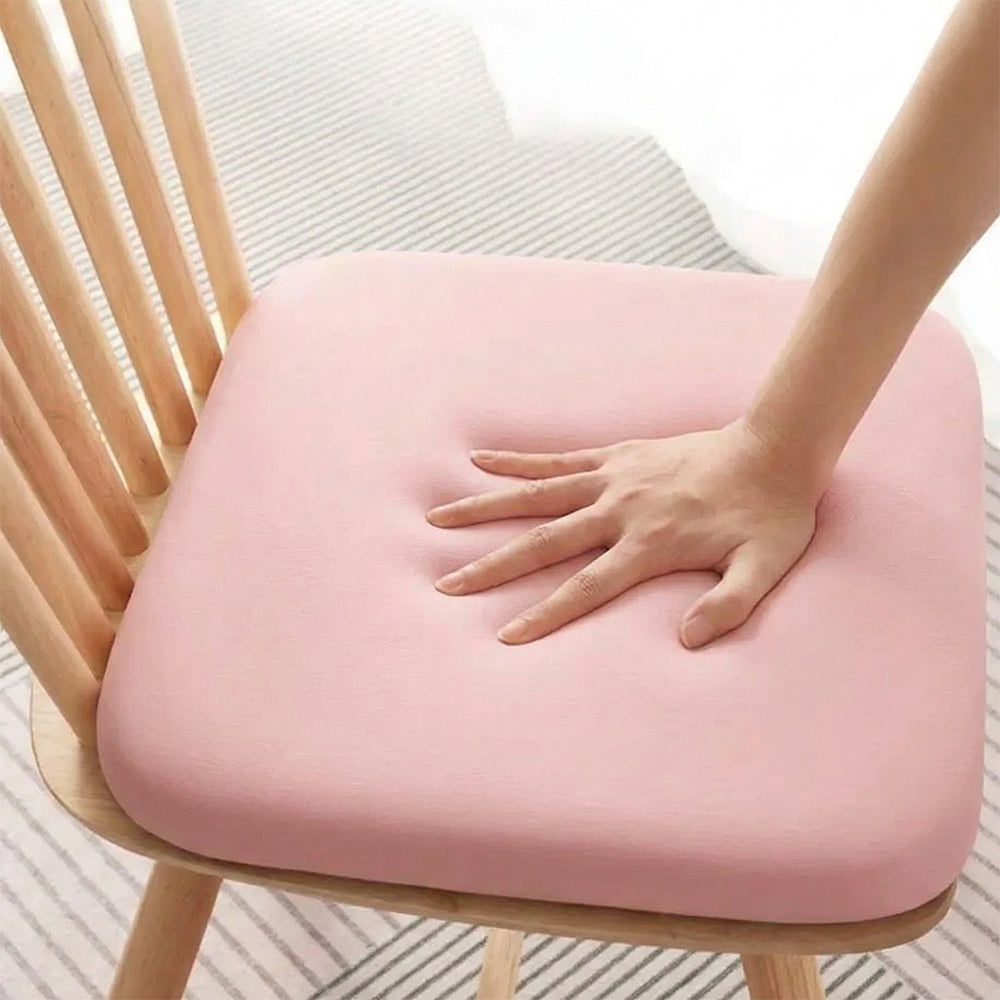 Un coussin mémoire de forme ultra doux confortable posé sur une chaise en bois, avec une main appuyant sur la surface pour montrer sa souplesse et son confort.