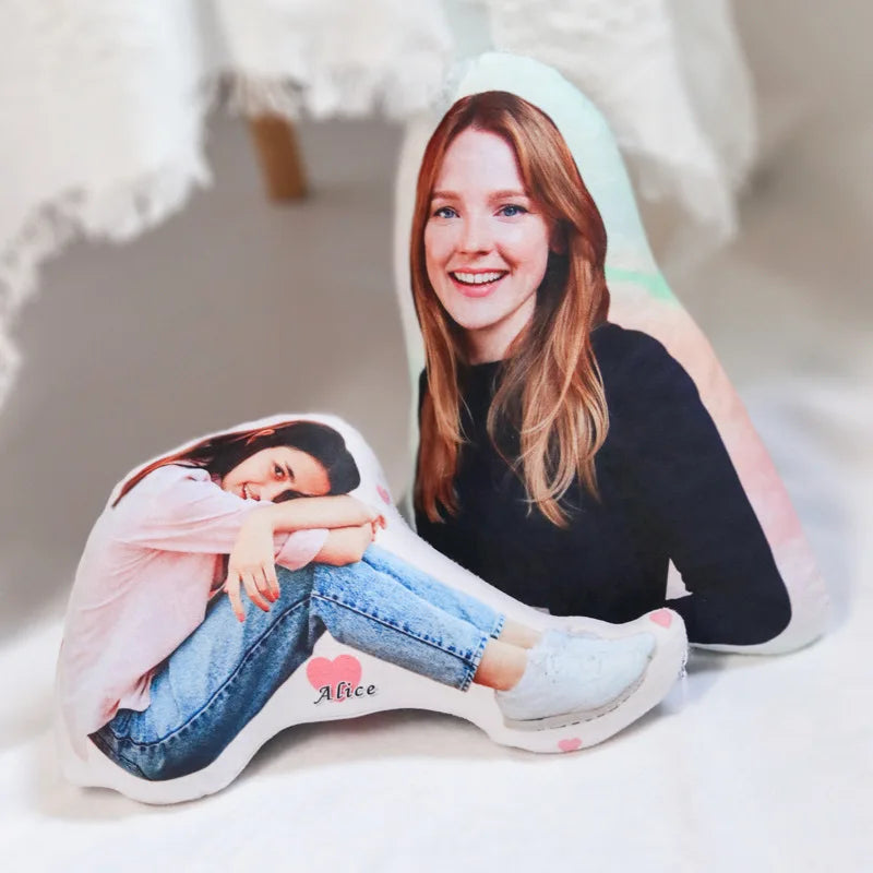 Un coussin personnalisé découpé à la forme d’une photo représentant une personne assise, posé sur un sol clair dans un intérieur doux et lumineux.