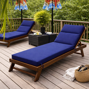 Un coussin pour transat épais avec dossier réglable posé sur une chaise longue en bois sur une terrasse, accompagné d’une table basse et d’un environnement verdoyant propice à la détente.