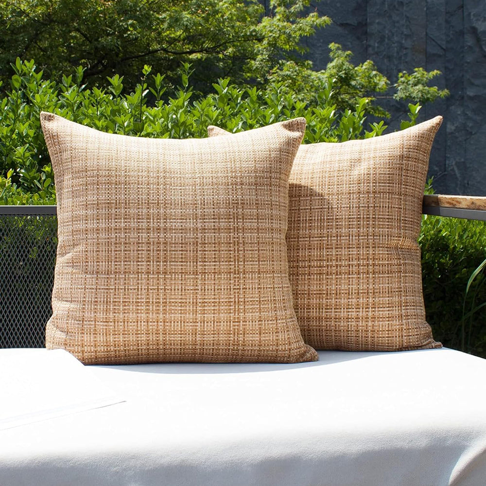 Coussin salon de jardin décoratif imperméable avec motif texturé, posé sur un banc d’extérieur clair au milieu de plantes et de fleurs, créant une ambiance élégante et accueillante.
