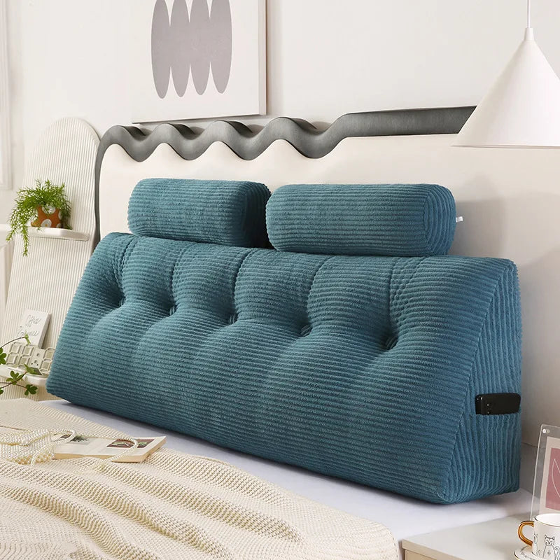 Coussin tête de lit décoratif capitonné avec lignes en relief et appui cylindrique intégré, installé contre une tête de lit ondulée dans une chambre moderne.