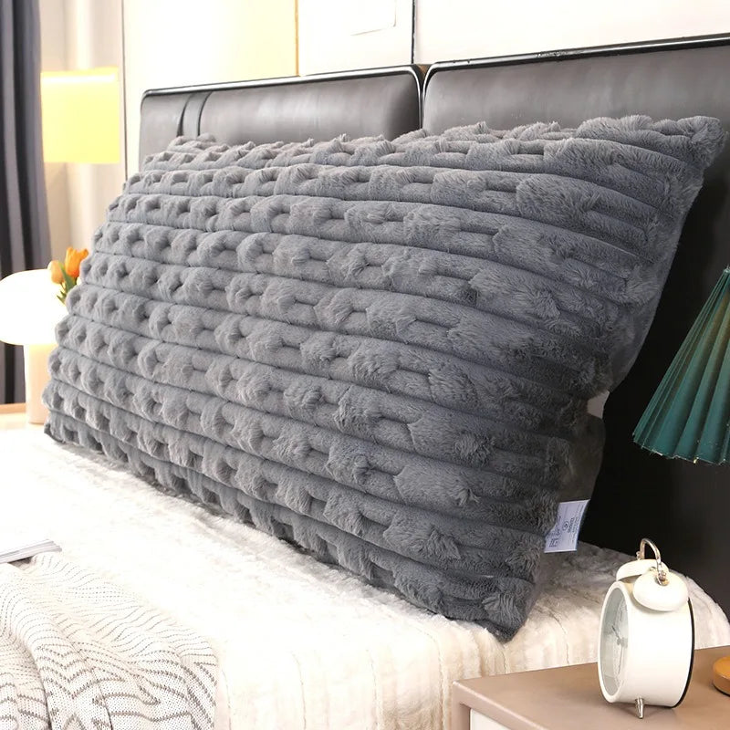 Coussin tête de lit doux et moelleux à texture duveteuse avec bandes en relief, installé contre une tête de lit, avec détail de fermeture éclair visible en gros plan.