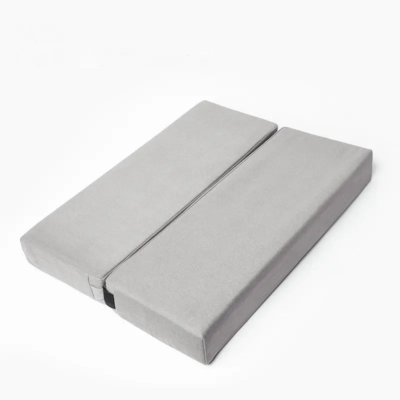Un coussin yoga rectangulaire design pratique, pliable, posé sur un fond neutre avec une surface lisse et des lignes épurées, idéal pour la méditation et le bien-être