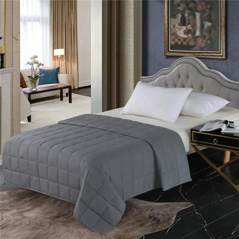 Une couverture lestée minimaliste et apaisante posée sur un lit élégant avec tête capitonnée, dans une chambre raffinée aux tons neutres et ambiance chaleureuse.