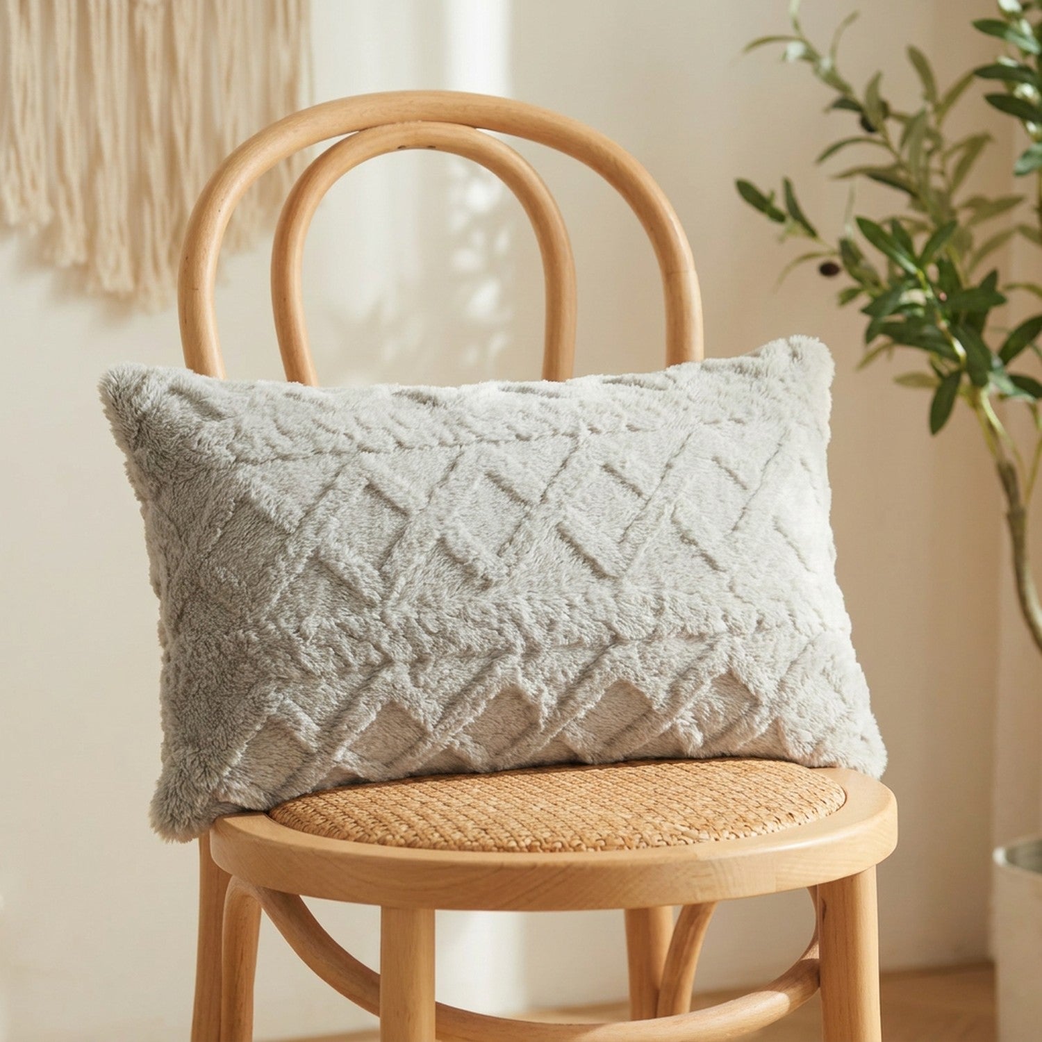 Housse de coussin lombaire en peluche gris clair à relief géométrique sur un fauteuil en bois