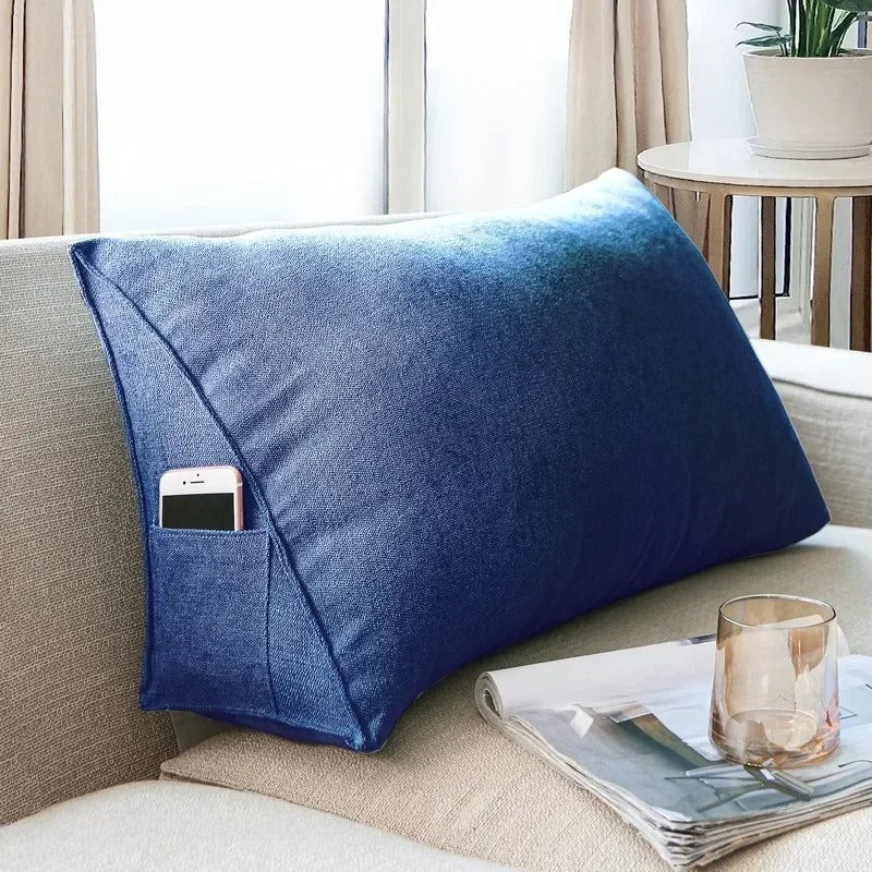 Gros coussin canapé au format généreux, posé sur une assise, avec une forme rectangulaire épaisse et une poche latérale intégrée, conçu pour offrir un confort enveloppant et pratique.