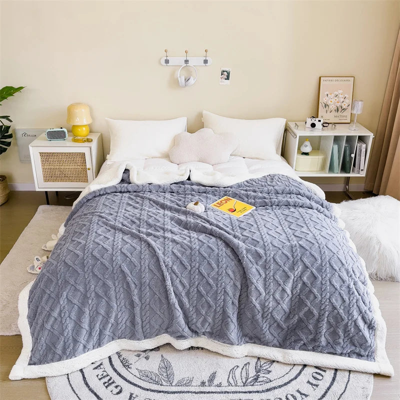 Une parure de lit cocooning double face épaisse et texturée posée sur un lit blanc, avec un côté doux effet laine visible à l’intérieur et une surface extérieure à motif relief.