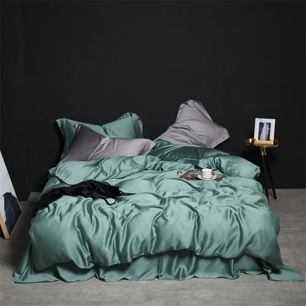 Une parure de lit luxe finition satinée aux reflets lumineux, présentée sur un lit avec plusieurs oreillers et une couette au tissu fluide, dans une chambre à l’ambiance élégante et minimaliste.