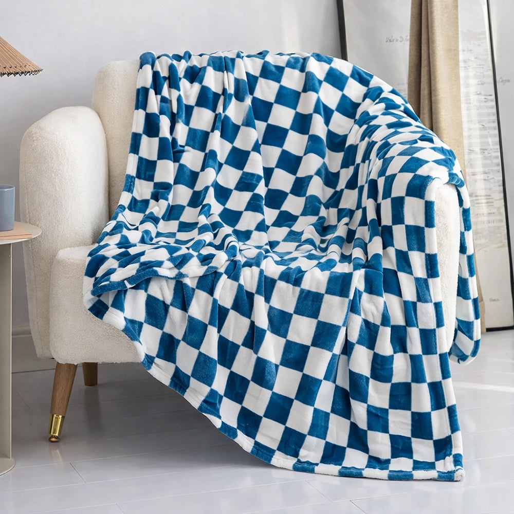 Un plaid canapé motif damier délicatement posé sur un fauteuil clair, avec un motif à carreaux réguliers créant un effet graphique et moderne dans un salon lumineux.
