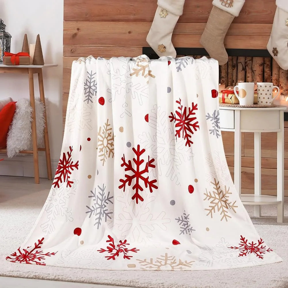 Un plaid Noël ambiance festive avec motifs de flocons hivernaux, posé devant une cheminée décorée avec des chaussettes de Noël dans un salon chaleureux.