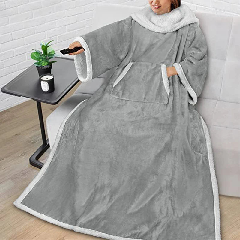 Un plaid avec manches enveloppant et une grande poche centrale, parfait pour se couvrir tout en gardant les bras libres pendant un moment de détente.