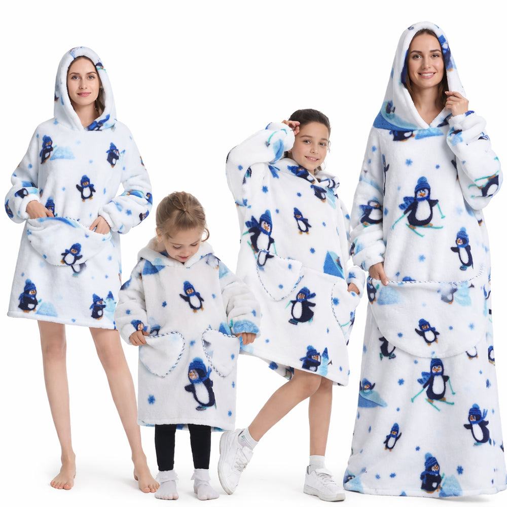 Un plaid avec manches oversize à capuche porté par des adultes et des enfants, coupe ample et enveloppante avec motifs ludiques, conçu pour rester bien au chaud à la maison.