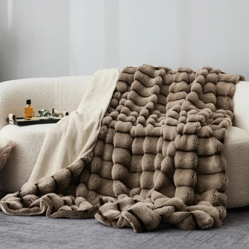 Un plaid chaud à rayures en relief, épais et texturé, délicatement posé sur un canapé avec un tombé généreux, créant une ambiance cosy et élégante.