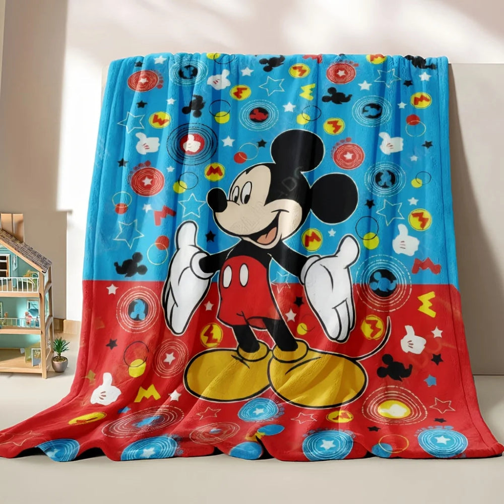 Un plaid enfant à imprimé Mickey Mouse représentant le personnage souriant avec des motifs ludiques, posé dans une chambre d’enfant pour une ambiance chaleureuse et joyeuse.