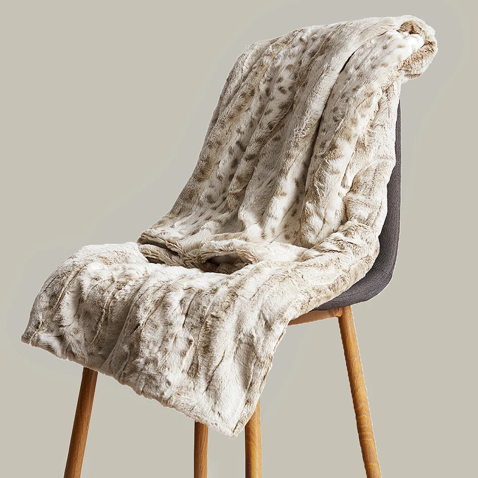 Un plaid léopard en fausse fourrure drapé sur une chaise, avec une texture duveteuse et un rendu élégant, parfait pour une ambiance chaleureuse.