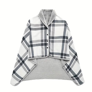 Un plaid poncho polaire à carreaux avec fermeture à boutons et col enveloppant, présenté à plat pour montrer sa coupe ample et sa doublure douce.