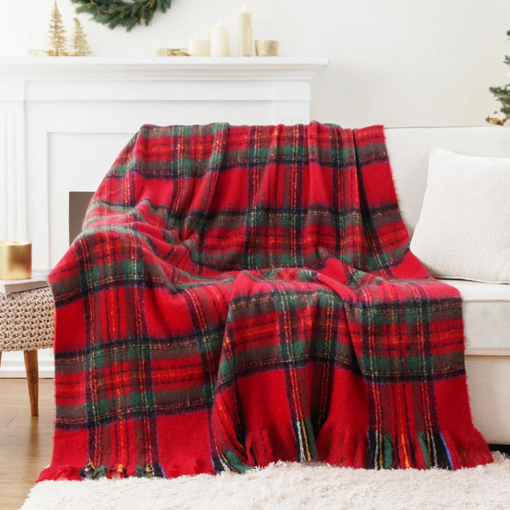 Un plaid tartan écossais à franges drapé sur un canapé clair dans un salon lumineux, avec un motif à carreaux traditionnel et des franges visibles sur le bord du textile.